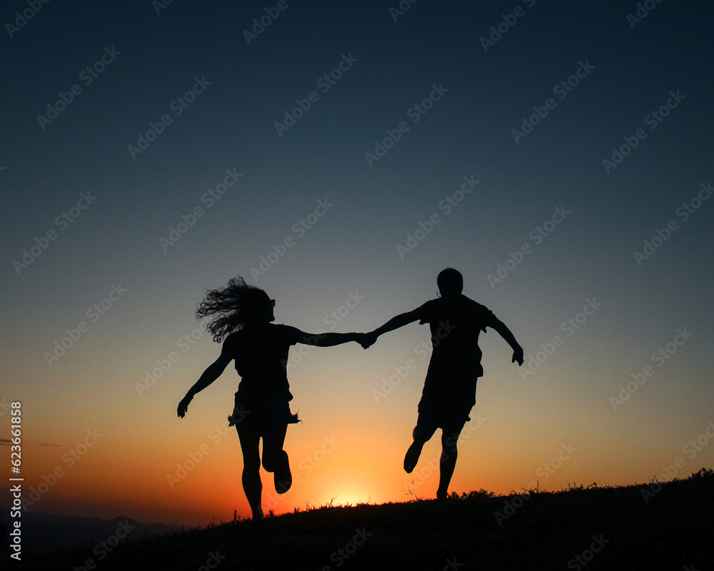Silhueta de casal de mãos dadas caminhando no pôr do sol 