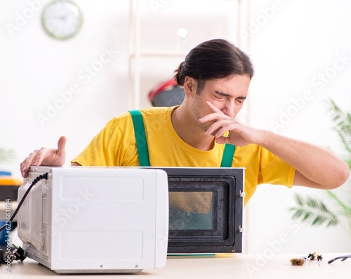 Young repairman repairing microwave in service centre