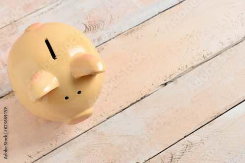 Piggy bank on light wooden background