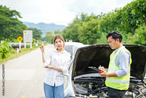 Closeup insurance company officers post a list of repairs on work list clipboard with woman driver acting point beside car accidents on road side.