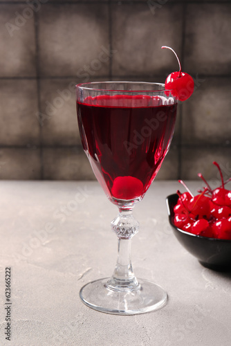 Glass of tasty cocktail with maraschino cherries on table