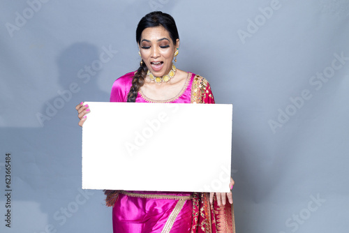 A Punjabi woman with sign board looking towards the camera studio shot photo