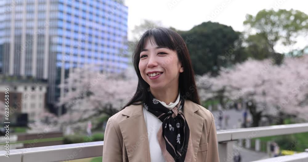 A 2x slow motion of Japanese woman portrait behind cherry blossom handheld