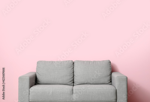 Cozy grey sofa near pink wall