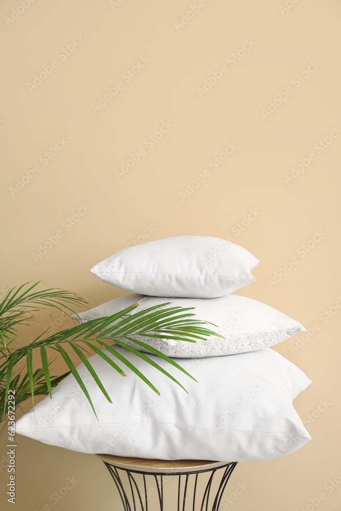 Table with white pillows and houseplant near beige wall Table with white pillows and houseplant near beige wall