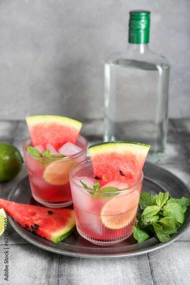 Glasses of tasty watermelon cocktail with lime and mint on grunge grey table near wall Glasses of tasty watermelon cocktail with lime and mint on grunge grey table near wall
