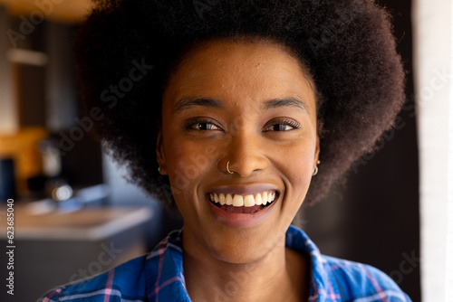 Portrait of happy african american woman with afro and nose ring smiling in kitchen