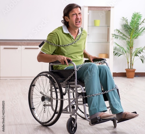 Young male invalid in wheel-chair suffering at home