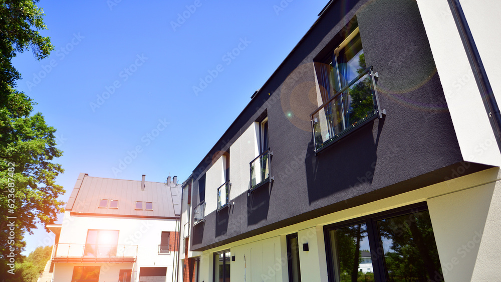 Fototapeta premium New single family houses in a new development area. Residential homes with modern facade. Terraced family homes in newly developed housing estate. The real estate market in the suburbs.