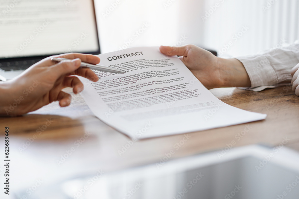 Fototapeta premium Businesswoman lawyer pointing into contract special points admitting something for colleague or client at the wooden desk in office. Business people teamwork and partnership, meeting concept