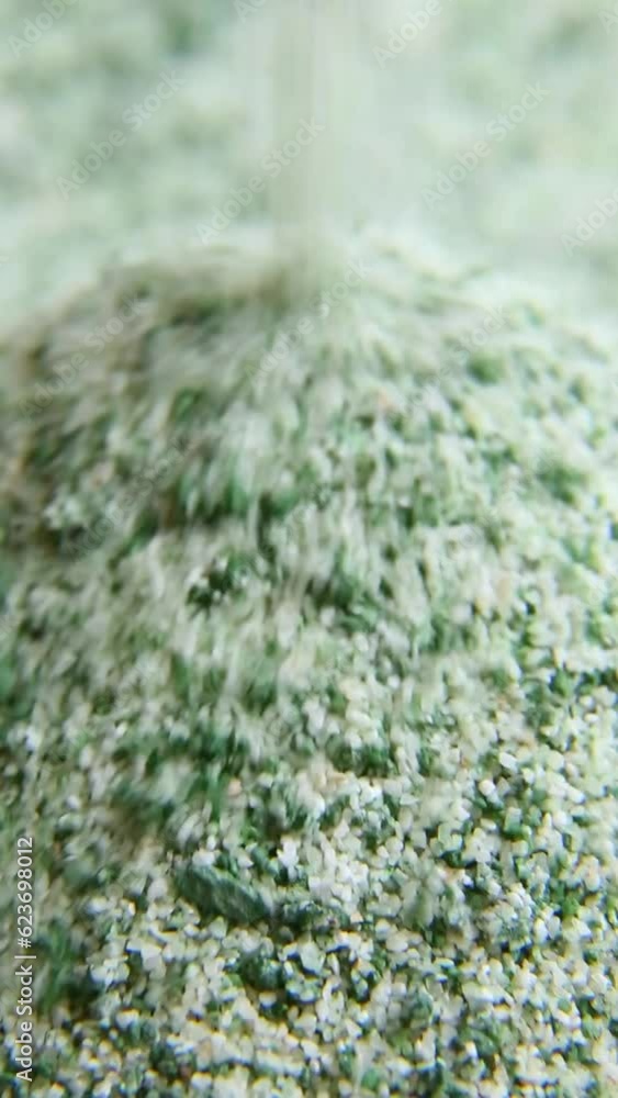 The green powder is poured into a slide. A jet of loose pale green substance crumbles. A continuous stream of green sand. Macro photography. ASMR The green powder is poured into a slide. A jet of loose pale green substance crumbles. A continuous stream of green sand. Macro photography. ASMR