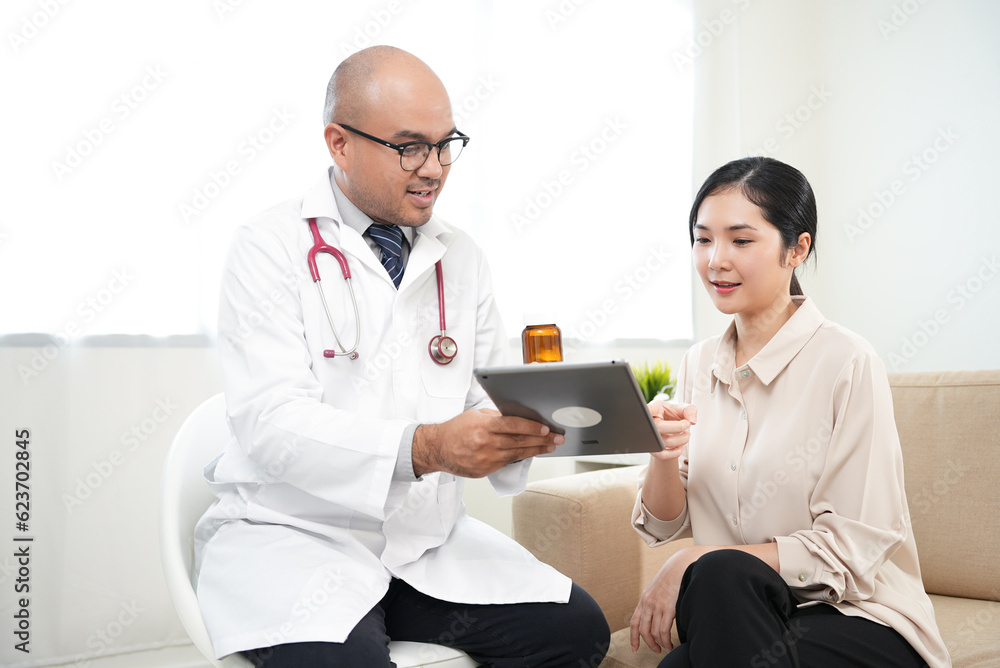 Smiley beautiful asian women patient consulting with Handsome asian professional doctor feeling happy about good news and The doctor writing and analyzing her symptoms on the tablet. Smiley beautiful asian women patient consulting with Handsome asian professional doctor feeling happy about good news and The doctor writing and analyzing her symptoms on the tablet.