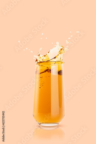 Apple yellow cool juice in glass with reflection, juicy splashes and drops fly pastel beige background, copy space, vertical. Ripe summer fruit gold drink with bubbles, swirl and splashing.