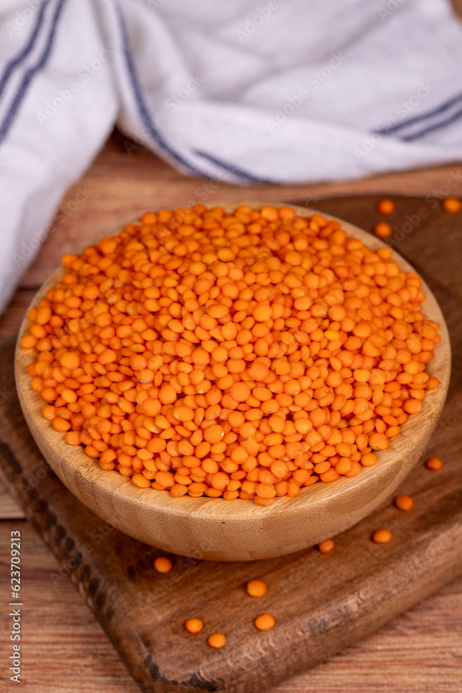 Red lentils on wood background. Raw red lentils in wooden bowl. Close up Red lentils on wood background. Raw red lentils in wooden bowl. Close up