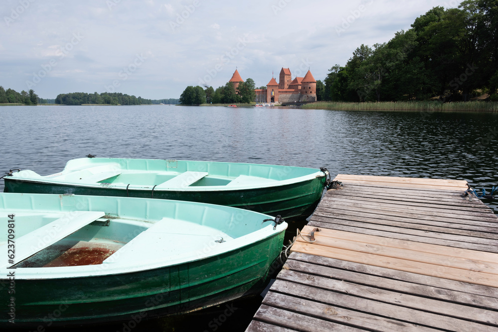 Wooden jetty with boats and on Lake Galve, in the background Trakai Castle Built in the 14th century and served as a residence for the Grand Dukes of Lithuania