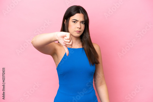 Young Brazilian woman isolated on pink background showing thumb down with negative expression