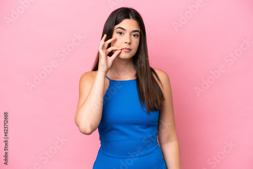 Young Brazilian woman isolated on pink background showing a sign of silence gesture