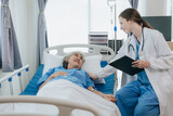 Friendly professional female doctor meeting an elderly patient on a hospital bed the concept of caring for the elderly.