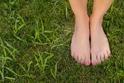 female feet stand barefoot on the green grass photo