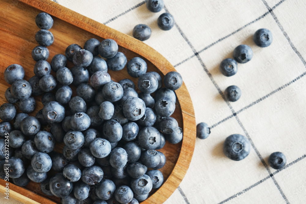 Blueberries lie in a wooden dish on a checkered tablecloth Blueberries lie in a wooden dish on a checkered tablecloth