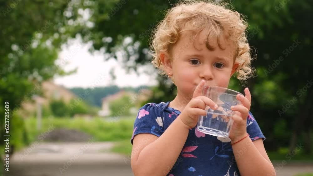 The child drinks water from a glass. Selective focus. The child drinks water from a glass. Selective focus.
