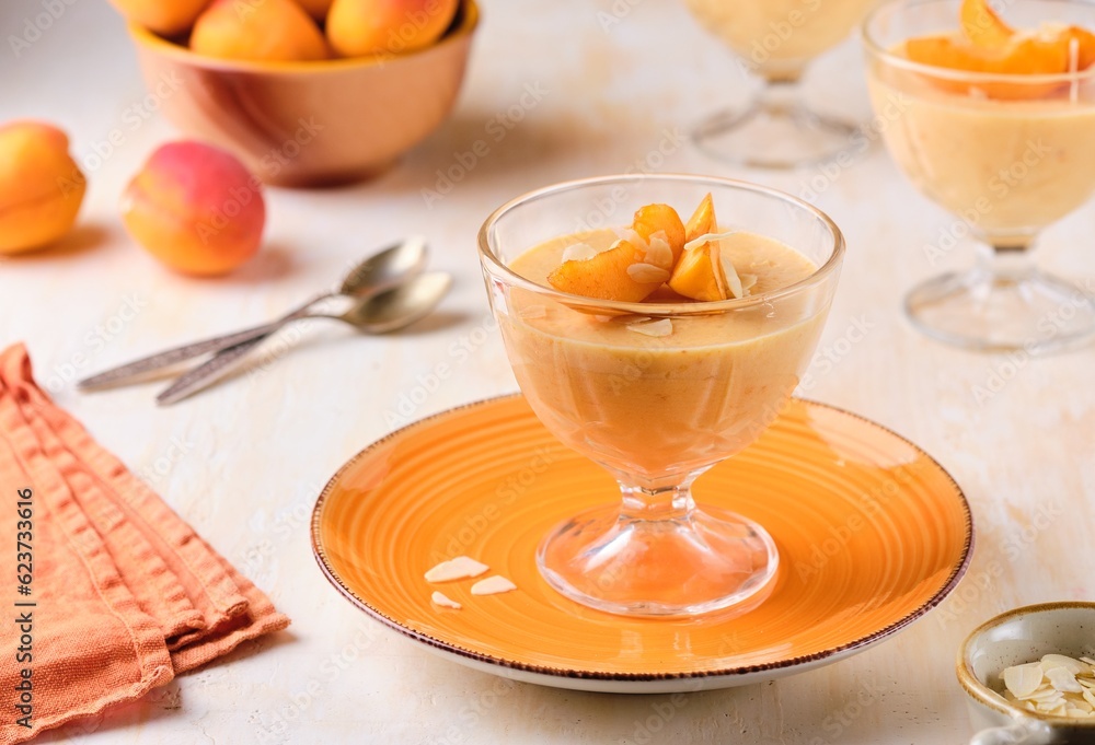Dessert, mousse or panna cotta with apricots and almond petals in transparent bowls on a light concrete background. Summer desserts, fruit mousses and jellies. Dessert, mousse or panna cotta with apricots and almond petals in transparent bowls on a light concrete background. Summer desserts, fruit mousses and jellies.