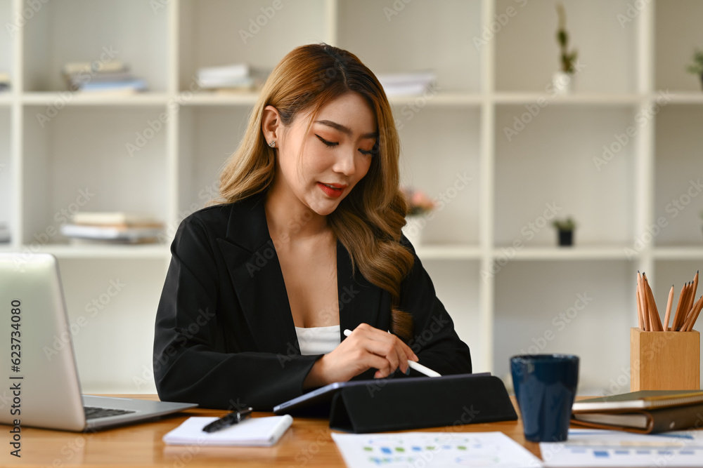 Millennial business lady using digital tablet and working on marketing strategy at modern office Millennial business lady using digital tablet and working on marketing strategy at modern office