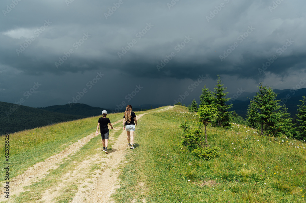 Mom with children walks in the mountains on the eve of a thunderstorm. People go down from the mountain to a safe place