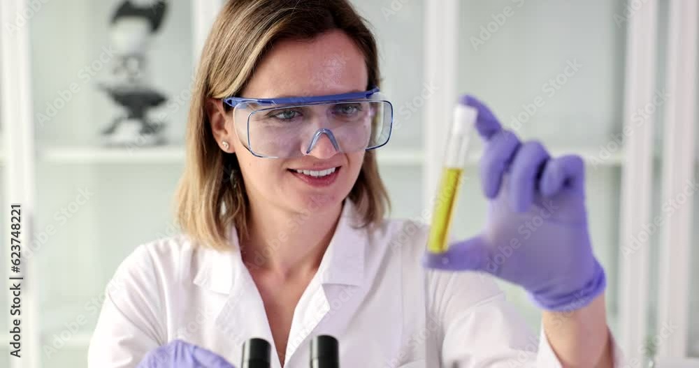Scientist testing natural product extract oil and biofuel. Scientist holding yellow color solution in chemistry lab Scientist testing natural product extract oil and biofuel. Scientist holding yellow color solution in chemistry lab