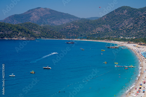 Tourists sunbathing and swimming on the Belcekiz (Belcegiz) Beach in Oludeniz (Blue Lagoon) district. Mugla, Turkey - July 10, 2023.