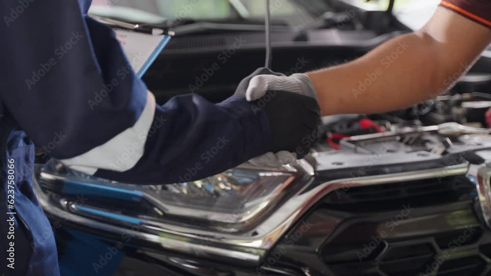 Close up of 2 mechanic hands in gloves making handshake in front of a car Close up of 2 mechanic hands in gloves making handshake in front of a car