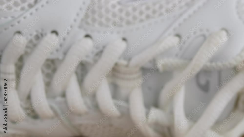 Close-up, Perforated White Leather Sneaker Surface Texture. Laces, mesh, holes, fabric structure. Side view. Blurred slow camera movement from toe to heel. Inside. Female shoe. Fitness. Sports. Close-up, Perforated White Leather Sneaker Surface Texture. Laces, mesh, holes, fabric structure. Side view. Blurred slow camera movement from toe to heel. Inside. Female shoe. Fitness. Sports.