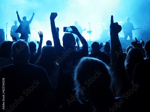 crowd of people attendíng a concert with raising hands