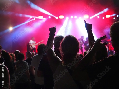 People with raising hands attendíng a live concert at night