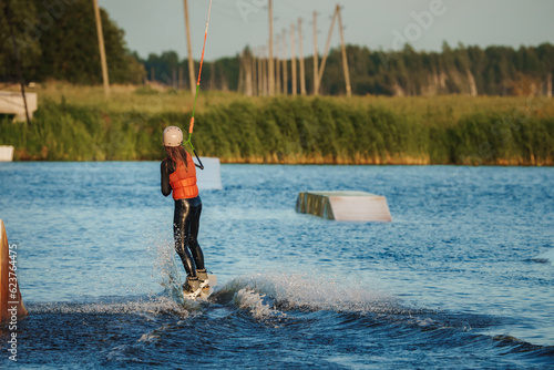 Wake boarding female sportsman girl jumping high wake boarding raley trick with huge water splash in the cable park photo