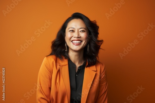 Portrait photography of a cheerful Chinese woman in her 30s wearing a chic cardigan against an abstract background  © Anne Schaum