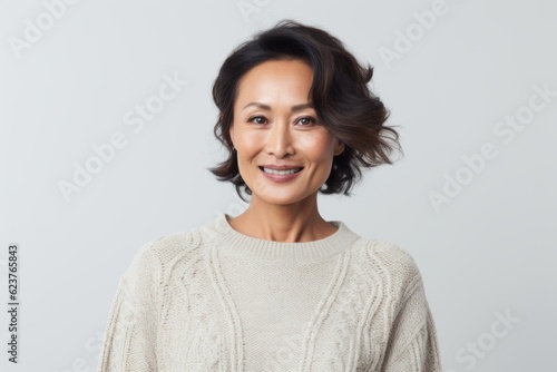 Portrait of smiling woman in sweater over grey background. Looking at camera