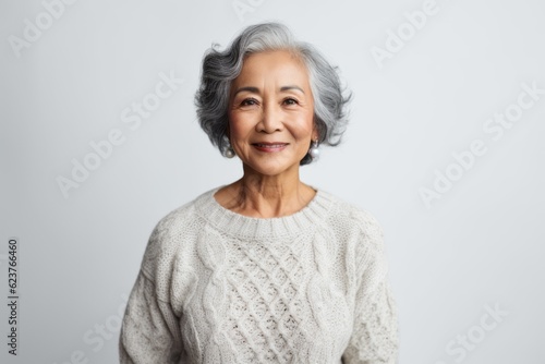 Portrait of a smiling senior asian woman standing against white background