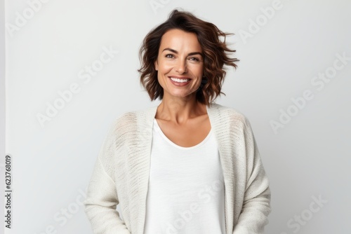 Portrait of a happy young woman smiling at the camera while standing against white background