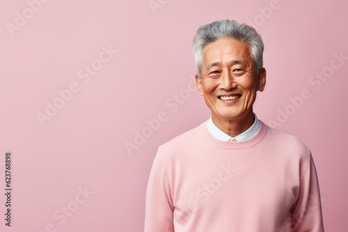 Portrait of a happy senior asian man looking at camera isolated over pink background
