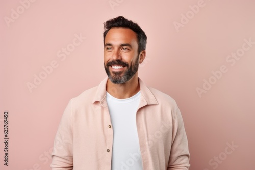 Portrait of a handsome young man smiling and looking at camera isolated over pink background