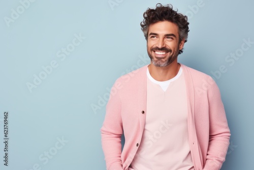 Portrait of a handsome young man smiling and looking at camera isolated over blue background