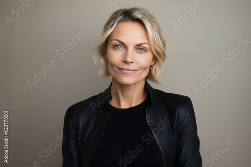 Portrait of beautiful mature woman with short blond hair, wearing black leather jacket, looking at camera.