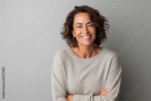 Portrait photography of a happy Brazilian woman in her 50s wearing a cozy sweater against a minimalist or empty room background 