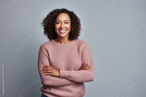 Portrait of a smiling african american woman standing with arms crossed against grey background