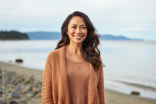 smiling woman on the beach over lake background, wearing warm sweater