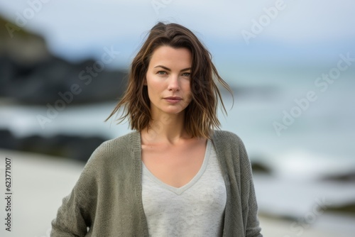 Portrait of a beautiful young woman standing on the beach with ocean in the background