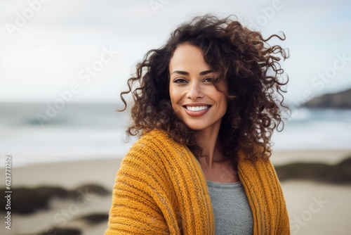 Portrait of a smiling young woman with curly hair at the beach © Robert MEYNER