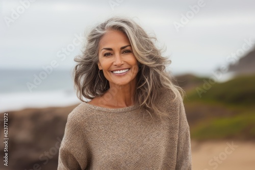 Portrait of a beautiful mature woman smiling at the camera on the beach © Robert MEYNER