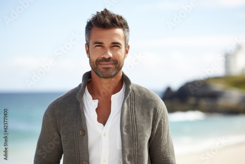 Portrait of handsome man standing on beach with ocean in the background